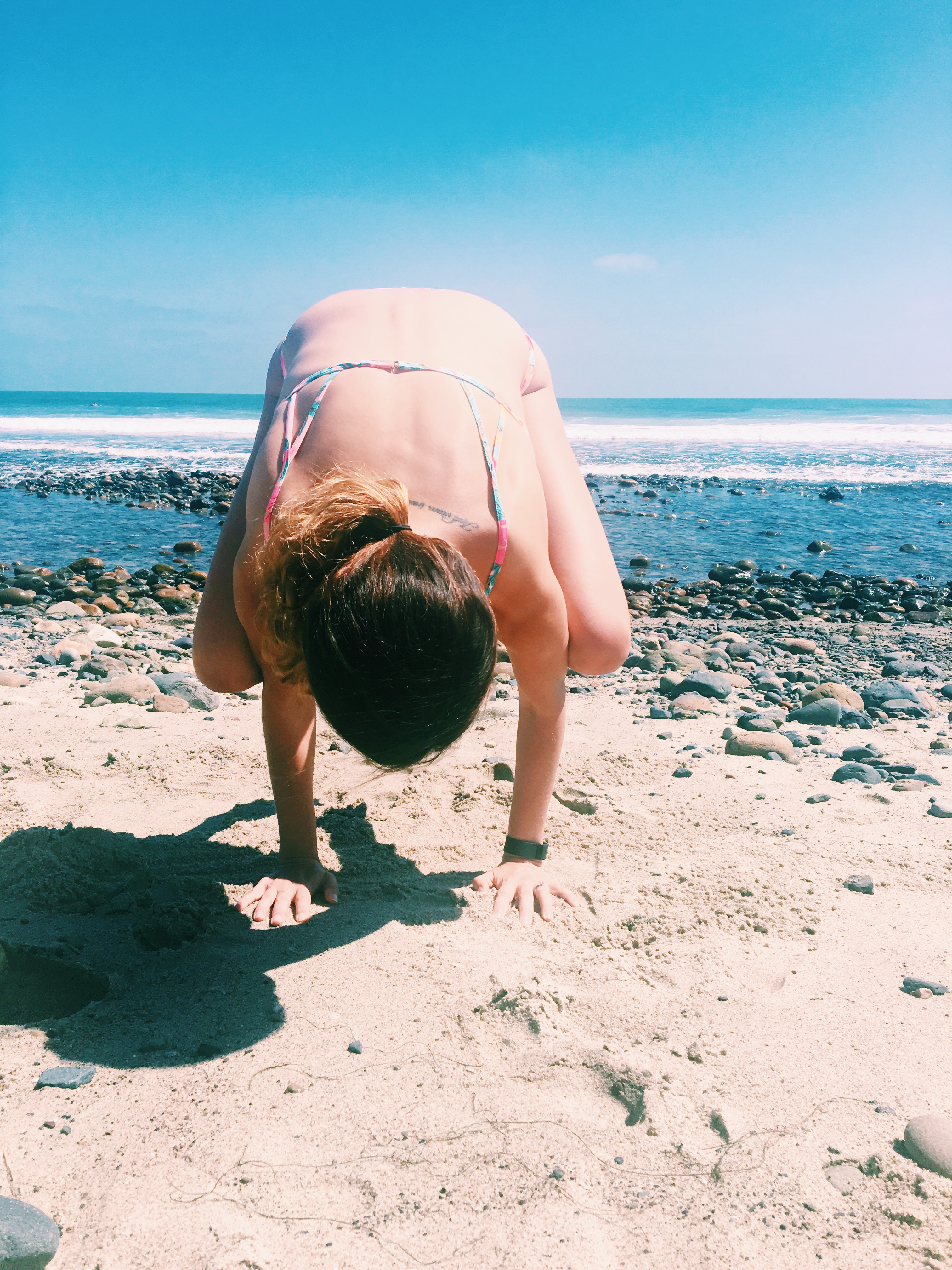 doing crow pose, yoga, on the beach in southern california
